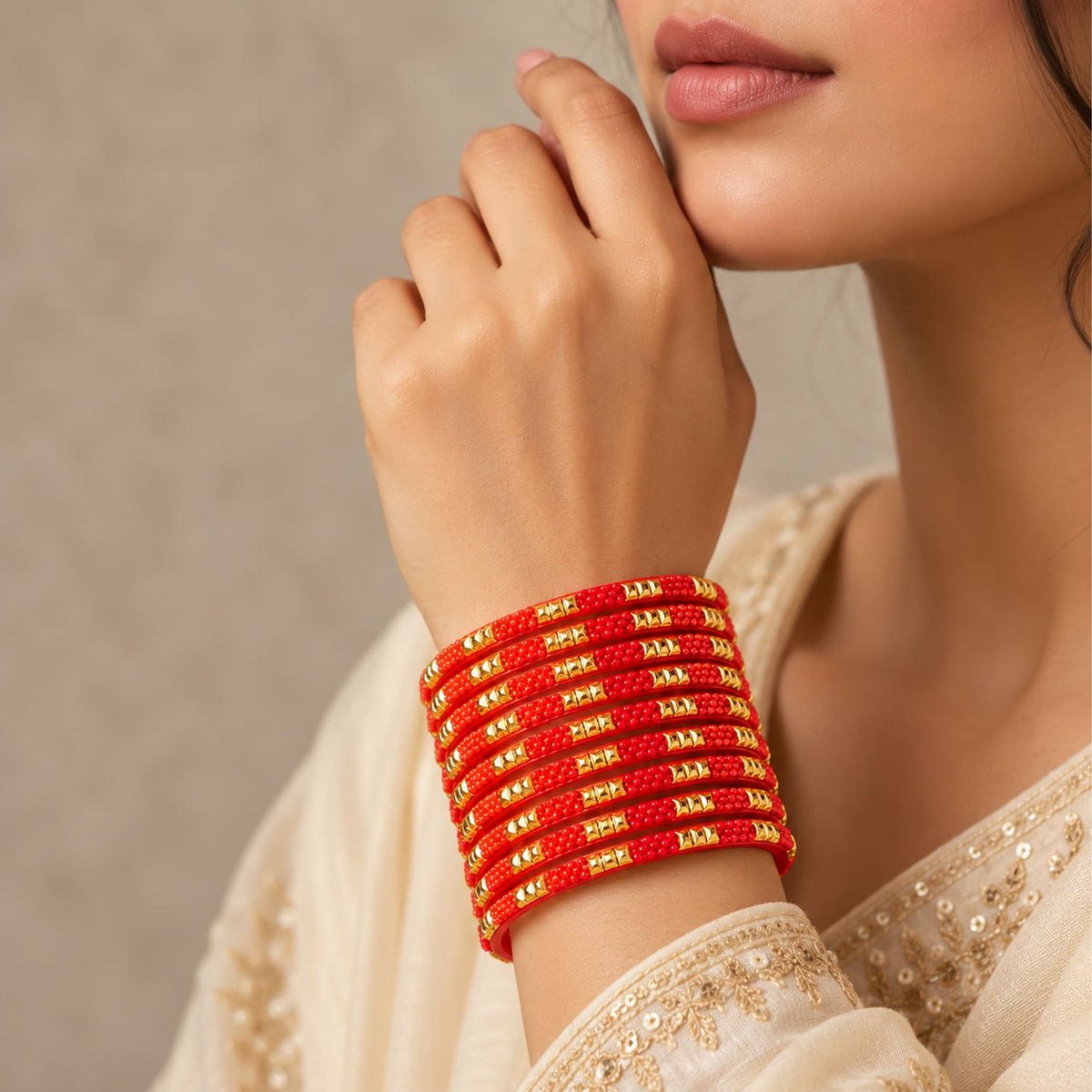 A stack of 12ct vibrant red glass bangles with intricate gold-tone geometric patterns handcrafted for bridal wear