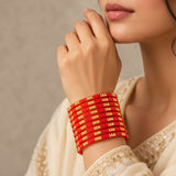 A stack of 12ct vibrant red glass bangles with intricate gold-tone geometric patterns handcrafted for bridal wear