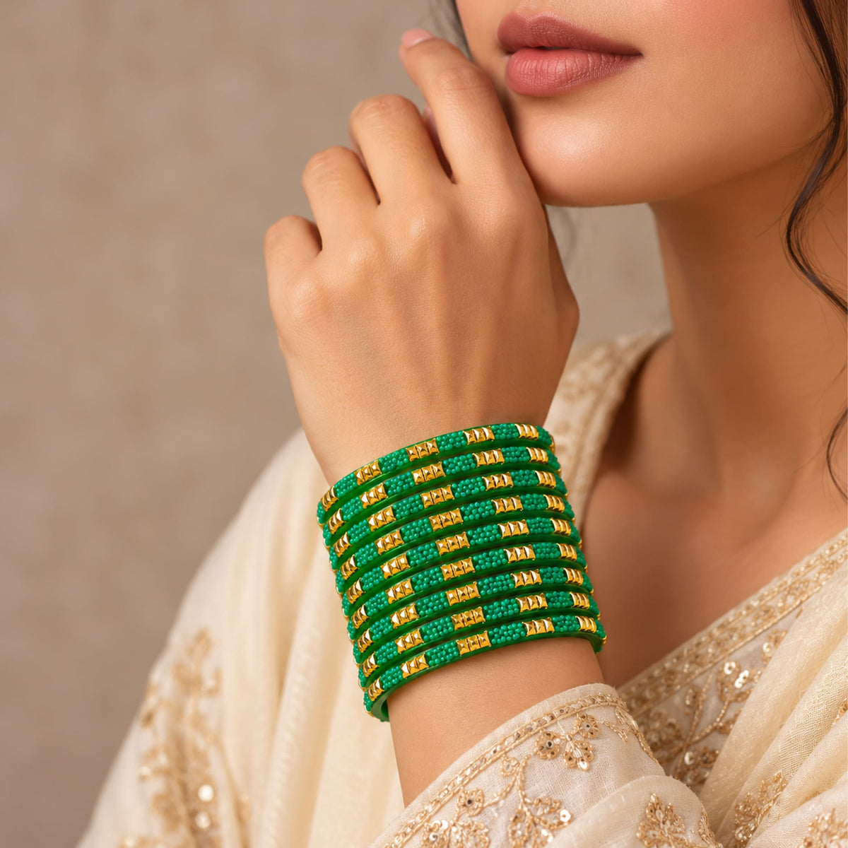 Green and gold glass bangles stacked on a wrist from a 12ct colorful bridal bangle set handcrafted for weddings