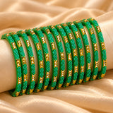 A set of vibrant green glass bangles with gold-tone rectangular embellishments and delicate beadwork for bridal wear