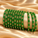A set of vibrant green 12ct glass bangles adorned with sparkling gold toned stones on a cream display for bridal gifting