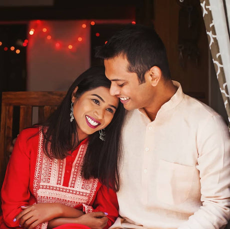 Couple embracing and smiling, with the woman wearing a vibrant red traditional outfit.