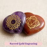 Two heart-shaped purple amethyst and reddish-brown jasper crystal reiki stones with gold engraved chakra symbols