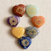 Set of seven heart-shaped polished chakra stones in unique colors with golden engraved geometric symbols for meditation and healing