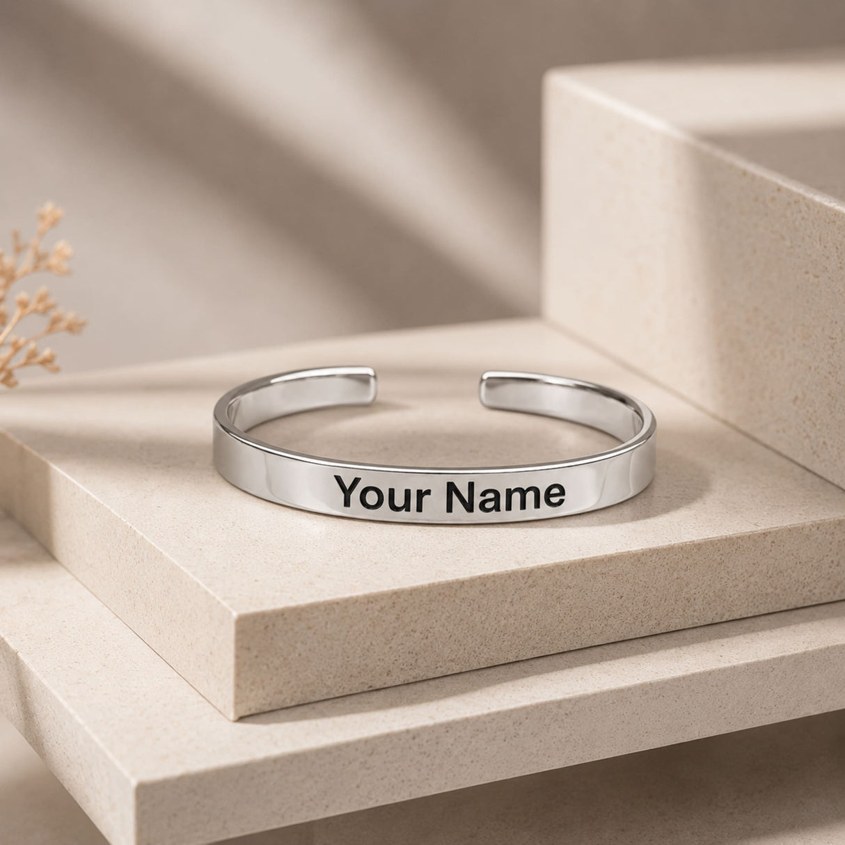 A sleek silver-toned metal cuff bracelet with minimalist design and engraved your name on the inner surface