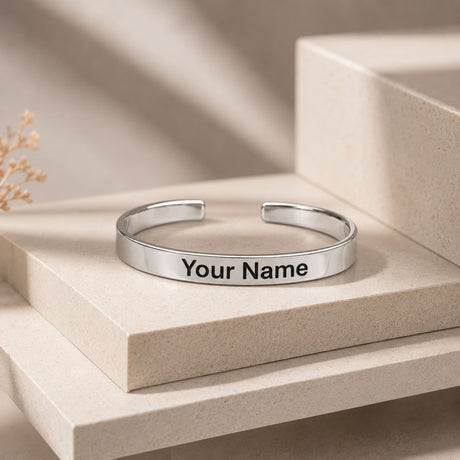 A sleek silver-toned metal cuff bracelet with minimalist design and engraved your name on the inner surface