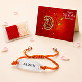Personalized orange braided cord rakhi with a silver stainless steel plate engraved with the name Aiden for Raksha Bandhan