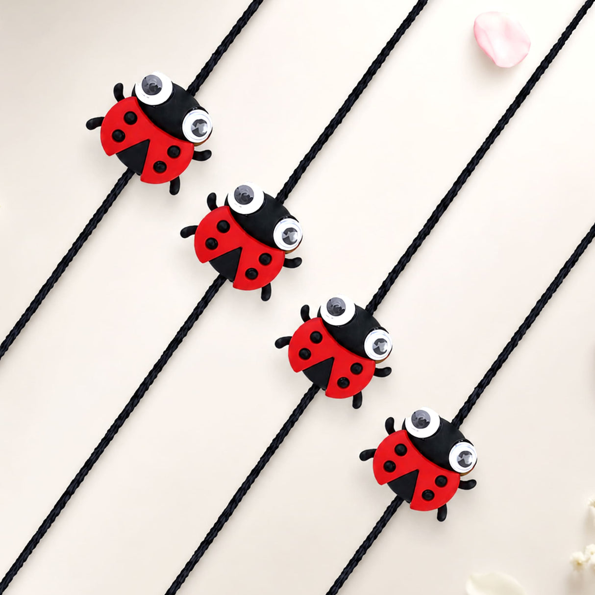 Cartoon animal rakhi for kids featuring red and black ladybug charms with googly eyes on black cords for brother protection
