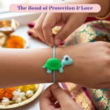 A green and light blue turtle-shaped rubber cartoon animal rakhi bracelet with a large eye worn on the arm