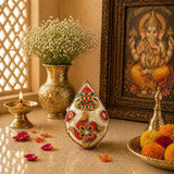 A decorative teardrop-shaped white shriphal mangal kalash coconut adorned with intricate red green and gold patterns for wedding and pooja use