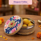 Navy blue floral gotta steel ladoo box with gold lace trim and red gem centerpiece