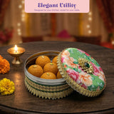 Green floral lid with gold trim and gem on Gotta steel ladoo box of golden sweets