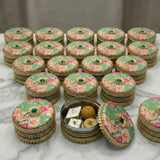 Green Gotta Steel Ladoo Box with floral gold jeweled design and sweets