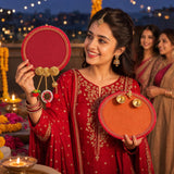 Red circular designer and decorative karwachauth thali with gold-trimmed edges and dangling ornaments for gifting
