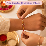 Designer rakhi gift hamper featuring a red and gold adjustable rakhi bracelet with red gemstone and white stones for raksha bandhan