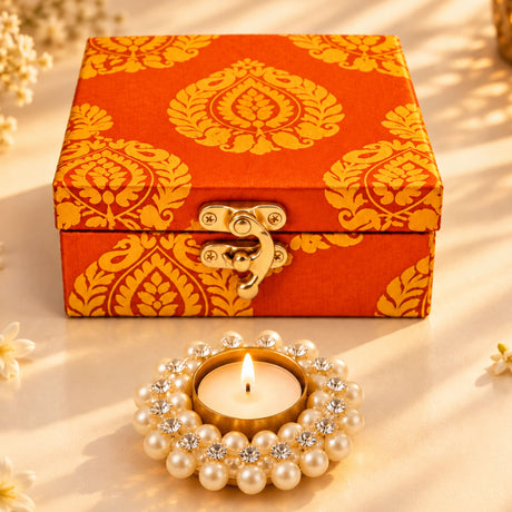 Ornate orange and gold brocade Diwali gift hamper box with brass clasp and candle holder for traditional festival gifting