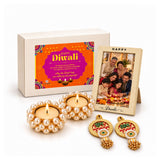 Pearl-encrusted golden diya holders with lit candles in a diwali gift hamper for family and friends