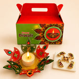 Red and green decorative diwali diya holder with lit candle adorned with swastika and gemstones for festive gifting