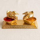 Double duck golden chopra brass spice holders with intricate patterns containing red and orange-yellow powders for pooja decor