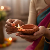Traditional terracotta diya with embossed patterns and glowing flame