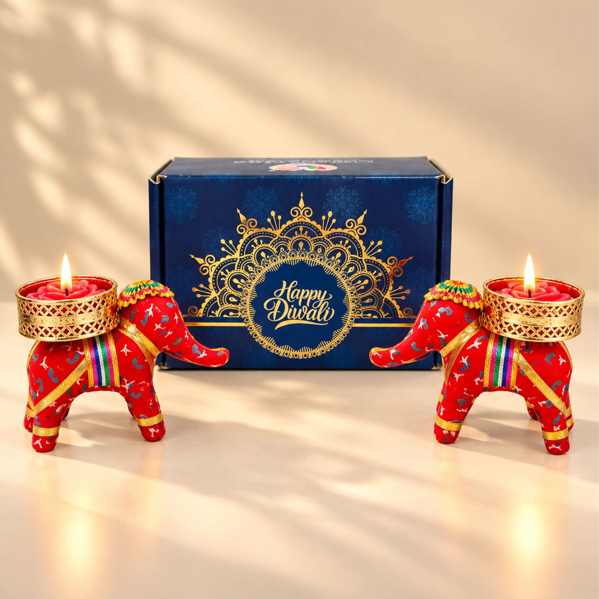 Red elephant-shaped handmade candle holders with gold accents and colorful straps for diwali gift hampers