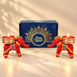 Red elephant-shaped handmade candle holders with gold accents and colorful straps for diwali gift hampers