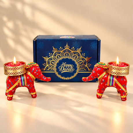 Red elephant-shaped handmade candle holders with gold accents and colorful straps for diwali gift hampers