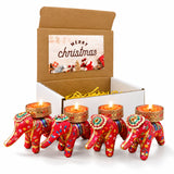 Gift box with four red elephant-shaped tealight holders with gold and colorful floral embroidery holding lit candles