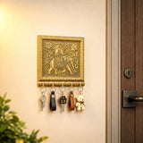 Golden ornate wall-mounted key holder with intricately engraved elephant and floral design holding five keys and teddy bear charm