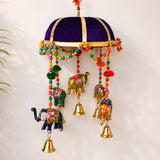 Purple velvet dome with gold trim hangs above colorful beaded chains and painted elephant ornaments with golden bells in rajasthani elephant door hanging for home decor