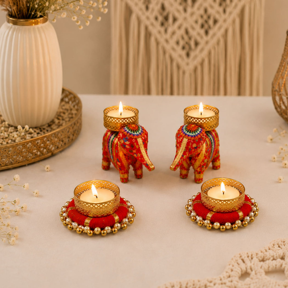 Two ornate red and gold elephant-shaped tealight holders with intricate beadwork and metallic accents for festival decor