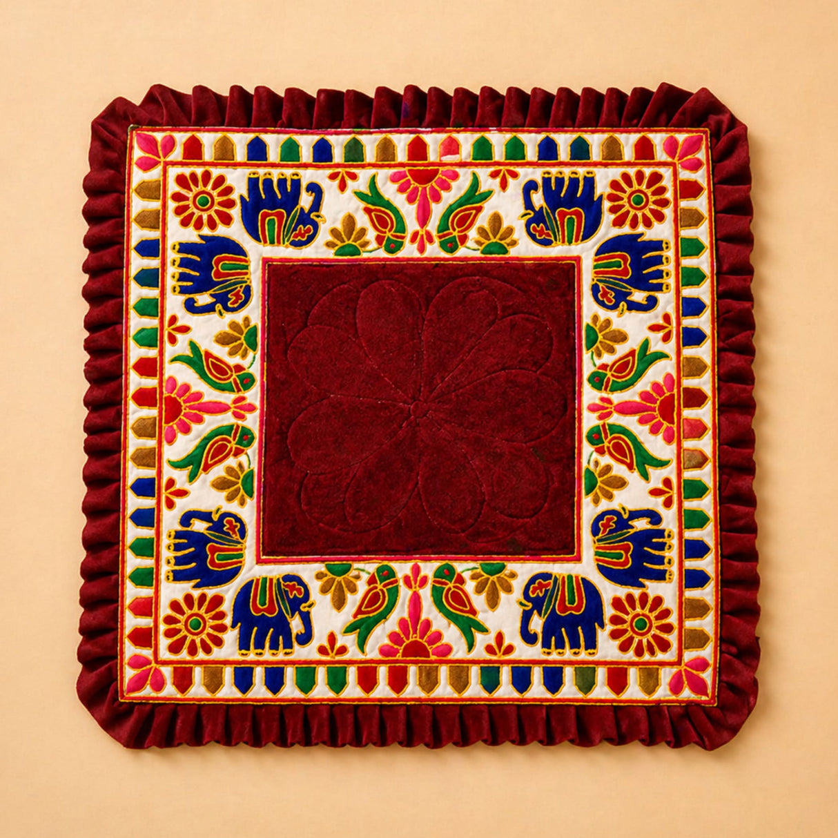A rich maroon velvet elephant pooja aasan rug with embroidered blue elephants and floral motifs for Ganesh pooja
