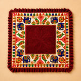 A rich maroon velvet elephant pooja aasan rug with embroidered blue elephants and floral motifs for Ganesh pooja