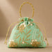 A mint green embroidered designer potli bag with gold and white floral patterns pearls and beaded handle for weddings