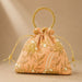 A peach-colored designer potli bag with embroidered gold floral details pearl embellishments and a beaded golden handle