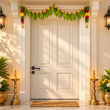 White paneled door decorated with fabric green mango leaf door toran featuring red and yellow flowers for pooja decor