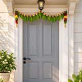 Fabric mango leaf door toran with floral hanging bandarwal in green and red adorning gray four-panel door for pooja decor