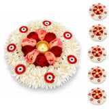 Decorative floral rangoli mat with central golden candle holder, red and pink roses, white flowers, and red white eye motifs