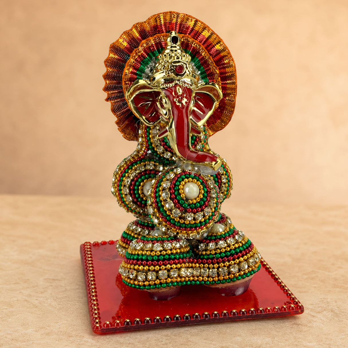 A vibrant beaded ganesh figurine supari with red trunk and golden accents for hindu wedding and pooja decor