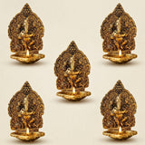 Golden brass ganesha diya oil lamps with intricate carvings and lit candles for puja and diwali decor