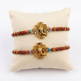 Two golden ganesha designer rakhi bracelets with ornate stone centerpiece and brown wooden beads for raksha bandhan