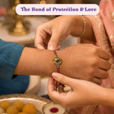 Designer Ganesha rakhi with gold-colored intricate design and red beads for brother and bhabhi on Raksha Bandhan