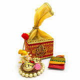 Red and gold ornate potli basket box with golden ganesha motif tied with yellow sheer fabric for hindu religious gifts