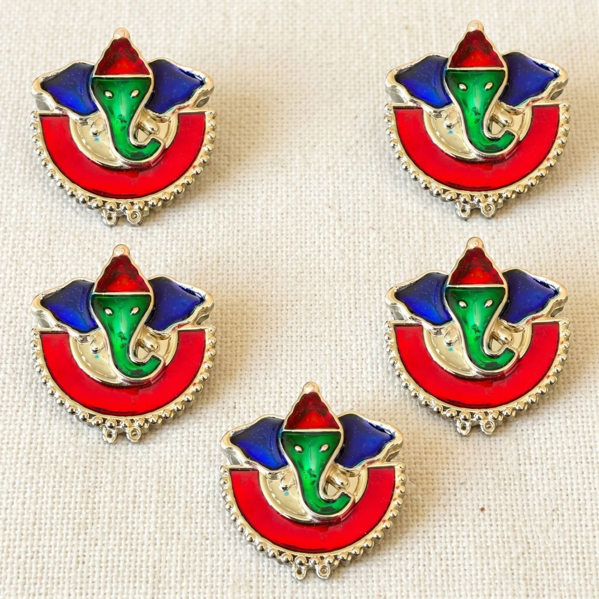Vibrant enamel ganesha-themed haldi kumkum holder with silver-toned frame in bold red green and blue colors for indian festivals