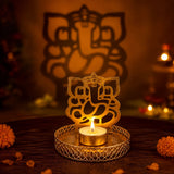 Golden metal ganesha-shaped candle holder with intricate cut-out design holding a lit tea light for festive pujas