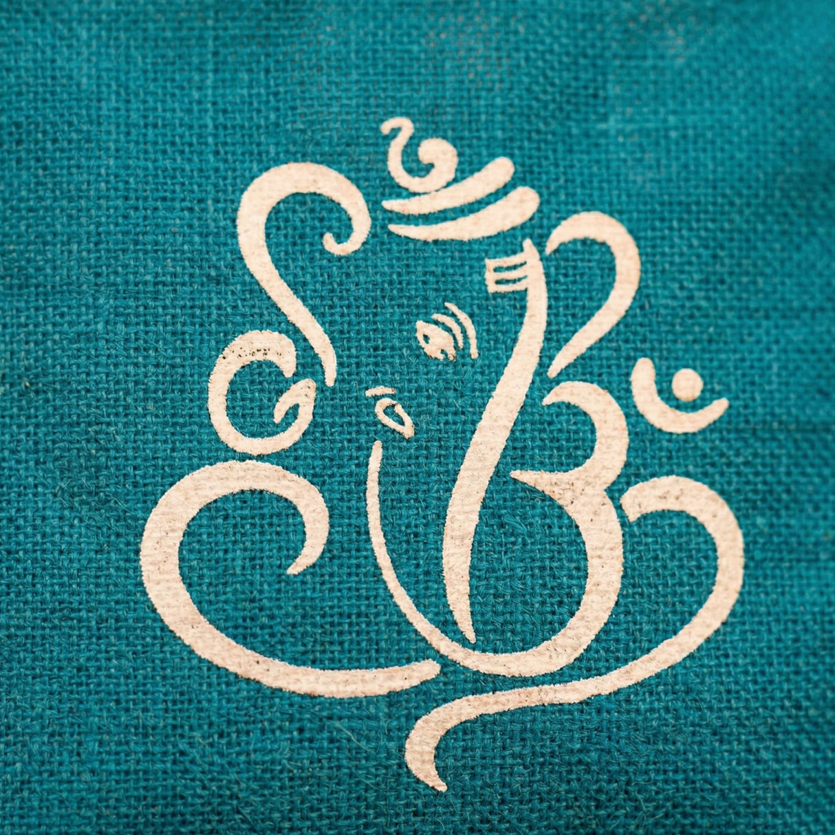 Teal burlap jute bag featuring a cream stylized ganesha om symbol for eco-friendly pooja gift and return favors