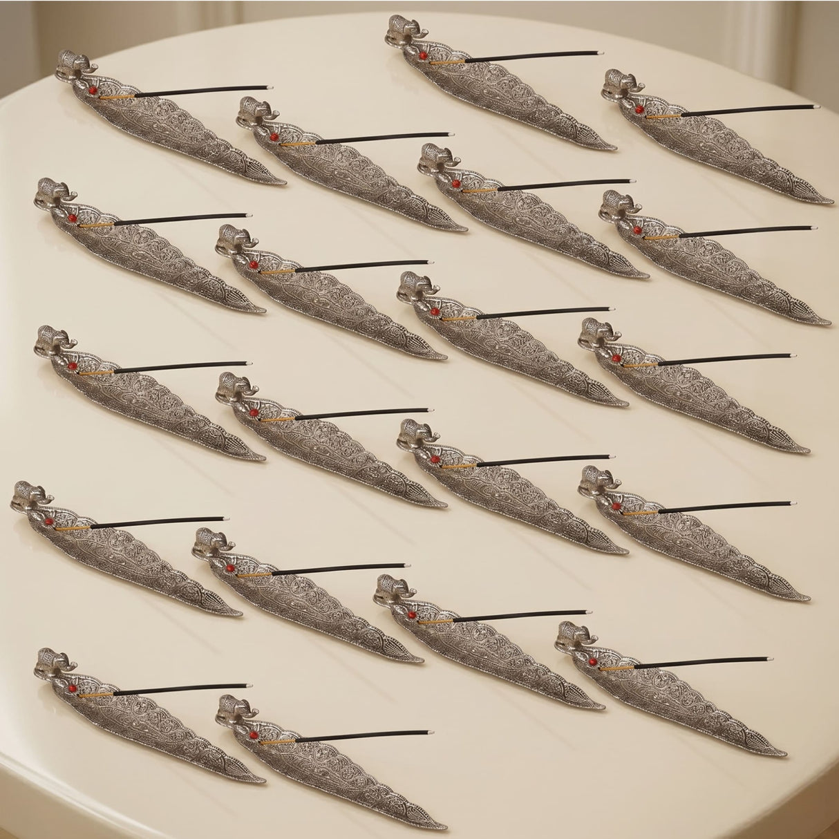 Silver leaf incense holder with intricate filigree designs and small red gemstone accents for home use