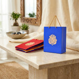 Blue paper gift bag with gold ganesha emblem and matching gold handles for wedding and ganesh chaturthi gifts