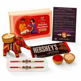 Designer ganesha rakhi gift hamper featuring a red and gold ornate elephant-shaped candle holder for brother and bhabhi