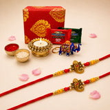 Red and gold brocade rakhi bracelets with intricate ganesha designs in a traditional raksha bandhan gift box hamper